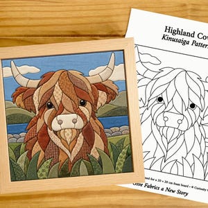 May include: A framed Kinusaiga fabric art piece depicting a Highland cow in shades of brown, tan, and green, alongside a printed paper pattern titled Highland Cow Kinusaiga Pattern, which includes text noting it is for a 20 x 20 cm foam board.