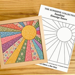 Puede incluir: Una pieza de arte Kinusaiga cuadrada en un marco de madera clara que presenta un sol con rayos radiantes hechos de parches de tela floral multicolor, junto a una hoja de patrón blanca titulada THE SUNSHINE COLLECTION Sunshine Kinusaiga Pattern.