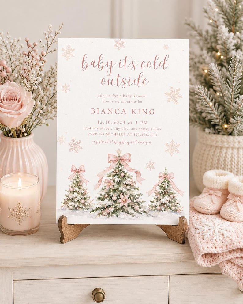 K&ouml;nnte beinhalten: Eine rechteckige Einladungskarte f&uuml;r eine Babyparty mit dem Text 'baby it's cold outside' in rosa Schreibschrift, illustriert mit drei verschneiten Weihnachtsb&auml;umen, die mit rosa Schleifen und Kugeln geschm&uuml;ckt sind, sowie Schneeflocken.