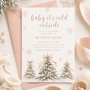 Um convite para chá de bebê com o texto "baby it's cold outside" em letra cursiva rosa, ilustrado com três árvores de Natal cobertas de neve e decoradas com laços e enfeites rosas sobre um fundo branco.