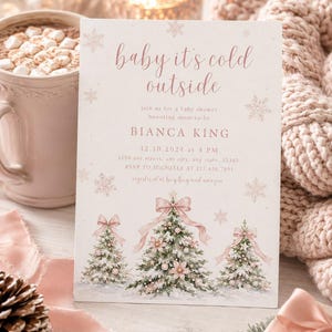 K&ouml;nnte beinhalten: Eine rechteckige Einladungskarte f&uuml;r eine Babyparty mit dem Text baby it's cold outside, Bianca King und Veranstaltungsdetails. Das Design zeigt drei verschneite Weihnachtsb&auml;ume, die mit rosa Schleifen und Kugeln verziert sind.