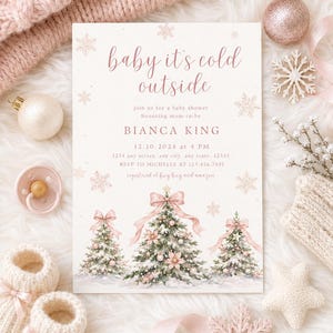 K&ouml;nnte beinhalten: Eine rechteckige Einladungskarte f&uuml;r eine Babyparty mit dem Text baby it's cold outside, Bianca King und Veranstaltungsdetails. Das Design zeigt Aquarellillustrationen von drei schneebedeckten Weihnachtsb&auml;umen mit rosa Schleifen und Kugeln.