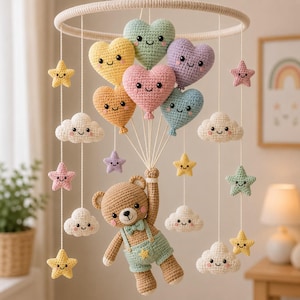 Peut inclure: Un mobile en crochet représentant un ours en peluche marron portant une salopette vert clair et un nœud papillon, suspendu par des fils attachés à un cadre circulaire. L'ours tient des fils reliés à six ballons en forme de cœur et des étoiles et nuages.