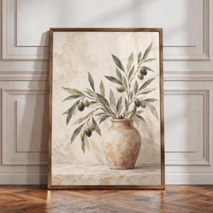 Könnte beinhalten: Ein gerahmter Kunstdruck mit einer strukturierten, hellen Keramikvase, in der sich belaubte Olivenzweige mit kleinen grünen und dunkelvioletten Oliven befinden. Das Kunstwerk ist vor einem neutralen, gesprenkelten Hintergrund platziert.