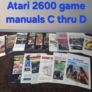 May include: A collection of Atari 2600 video game instruction manuals, including titles such as Combat, Cosmic Ark, Casino, Circus, Canyon Bomber, Dodge 'Em, Demon Attack, Donkey Kong, Demons to Diamonds, Defender, and Chopper Command.