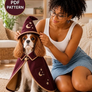 Könnte beinhalten: Ein burgunderrotes Haustier-Cape mit passendem spitzen Hut, verziert mit gestickten goldenen Halbmond- und Sternmotiven. Das Cape hat einen beigen Saum, einen Kragen mit Sternknopf und eine Tasche. Das Bild enthält ein Abzeichen mit PDF PATTERN.