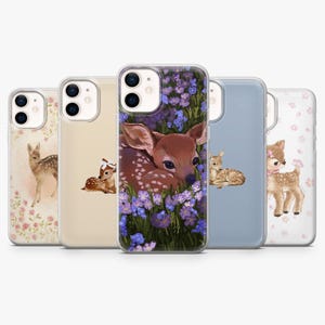 Peut inclure: Cinq coques de smartphone transparentes alignées, chacune présentant une illustration unique de faon. Les motifs incluent des faons entourés de fleurs roses, de fleurs bleues ou sur des fonds unis, avec une découpe pour double objectif.