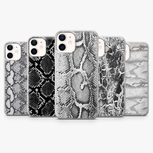 May include: Five smartphone cases arranged in a row, each featuring a distinct black, white, and grey snakeskin pattern. The cases have cutouts for dual rear camera lenses and are displayed against a plain, neutral background.