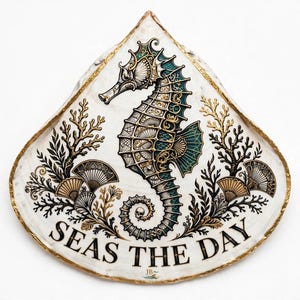 Könnte beinhalten: Eine tropfenförmige Dekoplatte mit einer detaillierten Illustration eines Seepferdchens in Türkis, Gold und Schwarz. Das Design zeigt Korallen- und Muschel-Motive mit dem Text SEAS THE DAY und den Initialen JB am unteren Rand.