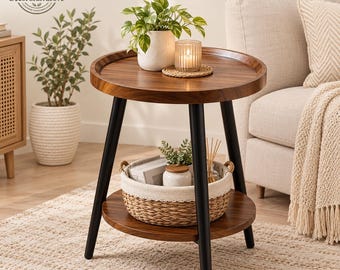 May include: A round side table with a dark wood grain top and bottom shelf, supported by three black metal legs. The top surface holds a potted green plant and a lit candle. A woven basket with a fabric liner sits on the lower shelf.
