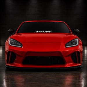 Puede incluir: Un coche deportivo de color rojo brillante visto desde el frente, con un parachoques aerodinámico elegante, faros oscuros y una pegatina blanca en el parabrisas con el texto japonés "スピードハンターズ" centrado en la parte superior.