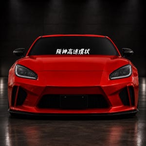 Könnte beinhalten: Ein leuchtend roter Sportwagen in der Frontansicht mit schwarzem Frontgrill, schlanken Scheinwerfern und dem weißen japanischen Schriftzug 阪神高速環状, der mittig auf dem oberen Teil der Windschutzscheibe vor dunklem Hintergrund steht.