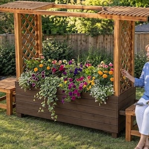 May include: A dark brown wooden planter box featuring a tall trellis back with a slatted top canopy. The planter is filled with a variety of colourful flowers including purple, yellow, and white blooms. Two matching wooden benches are attached.