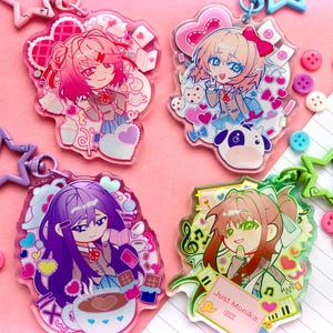 Könnte beinhalten: Vier Acryl-Schlüsselanhänger mit Anime-Figuren. Einer zeigt eine Figur mit rosa Haaren, einer mit einer Kuh, einer mit einer Kaffeetasse und der vierte mit einem Textfeld, auf dem Just Monika. OK. steht. Jeder hat einen sternförmigen Verschluss.