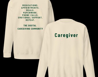 Puede incluir: Una sudadera de cuello redondo color crema con texto en verde oscuro. El frente muestra la palabra Caregiver. La parte posterior enumera: MEDICATIONS. APPOINTMENTS. MEALS. PAPERWORK. PHONE CALLS. EMOTIONAL SUPPORT. REPEAT. THE DIGITAL CAREGIVING COMMUNITY.
