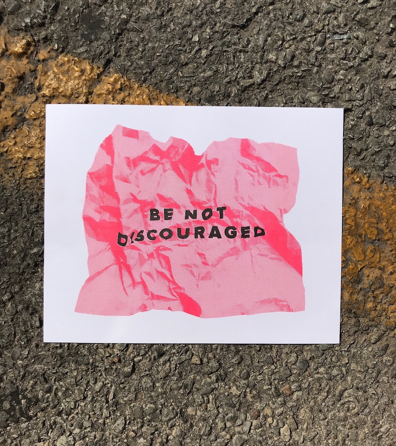 May include: A pink crumpled piece of paper with the text "BE NOT DISCOURAGED" printed in black.