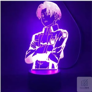 Puede incluir: Una lámpara LED con una silueta de acrílico grabada de un personaje de anime con cabello corto, que viste una chaqueta de estilo militar con un emblema en el hombro y el pecho. La figura está iluminada con una luz violeta vibrante.