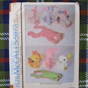 May include: A vintage McCall's pattern envelope, featuring fabric animal designs in two sizes. The envelope displays a variety of stuffed animal patterns, including a frog, duck, and bunny. The envelope is on a plaid background.