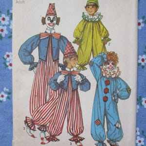 May include: Vintage sewing pattern featuring illustrations of four clown costumes. The costumes include colorful outfits with hats, ruffs, and striped pants. The pattern is labeled "Adult" at the top.