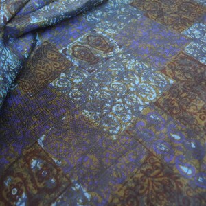 May include: A fabric with a blue, brown, and white patterned design. The pattern is a repeating geometric design with a paisley-like motif.