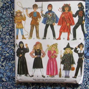 May include: A vintage sewing pattern featuring illustrations of various Halloween costumes. The costumes include a devil, witch, ninja, pirate, and other characters. The pattern is printed on white paper with a blue floral background.