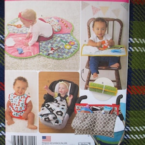 May include: A pattern sheet featuring baby items. The images show a baby play mat, a high chair with a tray, a bib, a car seat cover, and a stroller organizer. The items are in various colors and patterns, designed for infants and young children.