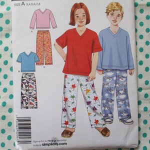 May include: A Simplicity sewing pattern for children's pajamas. The pattern features illustrations of a red V-neck shirt with floral print pants, a blue V-neck shirt with airplane print pants, and a pink V-neck shirt with floral print pants. The pattern includes sizes 3, 4, 5, 6, 7, and 8.