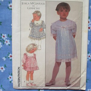 May include: Vintage sewing pattern featuring illustrations of children's dresses. The pattern includes designs for dresses with lace trim and decorative collars. The text "Jessica McClintock for Gunne Sax" is visible at the top of the pattern.