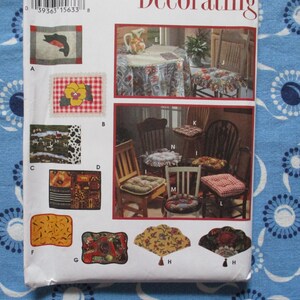 Op de afbeelding: Een vintage naaipatroon voor woondecoratieprojecten. Het patroon bevat verschillende ontwerpen voor stoelkussens, placemats en tafelkleden. De ontwerpen omvatten bloemen-, ruit- en rustieke thema's, met een verscheidenheid aan vormen en maten.