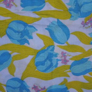 May include: A white fabric with a repeating pattern of blue and green tulips with yellow stems and pink flowers.