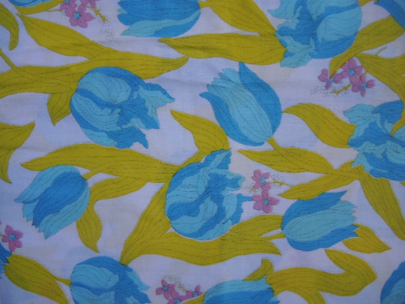 May include: A white fabric with a repeating pattern of blue and green tulips with yellow stems and pink flowers.