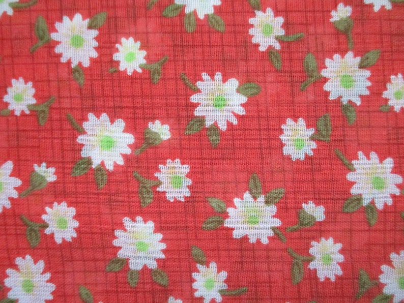K&ouml;nnte beinhalten: Roter Stoff mit einem wei&szlig;en Blumenmuster. Der Stoff hat ein Gittermuster und ist mit kleinen wei&szlig;en Bl&uuml;ten mit gr&uuml;nen Zentren bedeckt.
