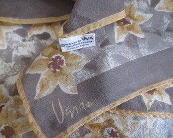 Peut inclure: Un foulard en soie gris avec un motif floral dans les tons de brun et beige. Le foulard a une bordure dorée et une étiquette qui indique "Scarves by Uma, 100% soie, fabriqué au Japon".