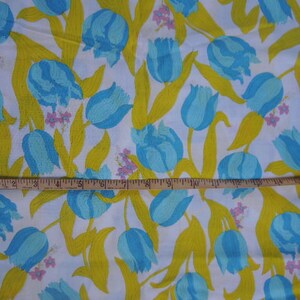 May include: White fabric with a repeating pattern of blue and yellow tulips. The fabric has a yellow background with blue tulips and green leaves.