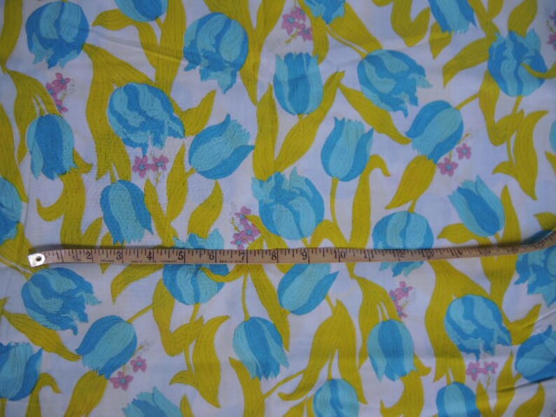 May include: White fabric with a repeating pattern of blue and yellow tulips. The fabric has a yellow background with blue tulips and green leaves.