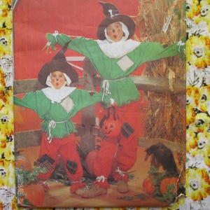 Pode incluir: Duas crianças vestidas de espantalhos, uma de verde e vermelho, a outra de verde e laranja, com uma abóbora na mão. As crianças estão em pé em frente a uma cerca de madeira e uma pilha de feno. A imagem é de um padrão de costura vintage.