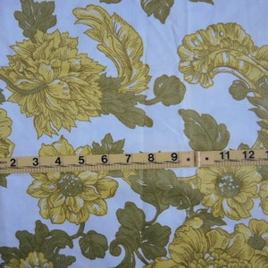 May include: White fabric with a repeating pattern of yellow flowers and green leaves. A ruler is placed across the fabric, showing measurements in inches.