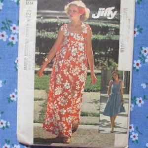 May include: A vintage dressmaking pattern for a medium-sized dress, showing a woman in a red floral maxi dress. The pattern is from Jiffy and includes a smaller image of a blue dress. The background is a blue floral fabric.