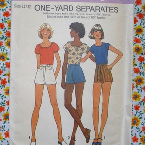 May include: A vintage sewing pattern titled "ONE-YARD SEPARATES" size 11/12. The illustration shows three figures wearing different tops and shorts. The tops include a red puff-sleeve top, a floral top, and a blue t-shirt. The shorts are white, denim, and striped.