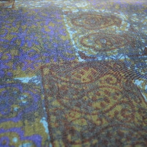 May include: A close-up of a fabric with a blue, purple, and brown paisley pattern.