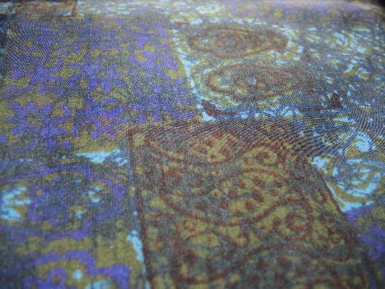 May include: A close-up of a fabric with a blue, purple, and brown paisley pattern.