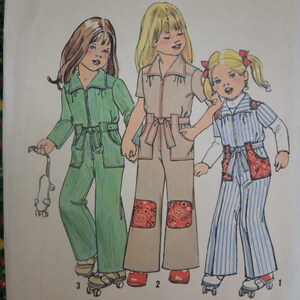 May include: A sewing pattern for three children's jumpsuits. The pattern includes a green jumpsuit with a white trim, a brown jumpsuit with a red and white pattern, and a blue and white striped jumpsuit.