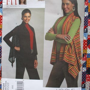 May include: A sewing pattern featuring two women modeling different outfits. One woman wears a black outfit with a patterned shawl, and the other wears a green top with a striped vest. The pattern is from Vogue.