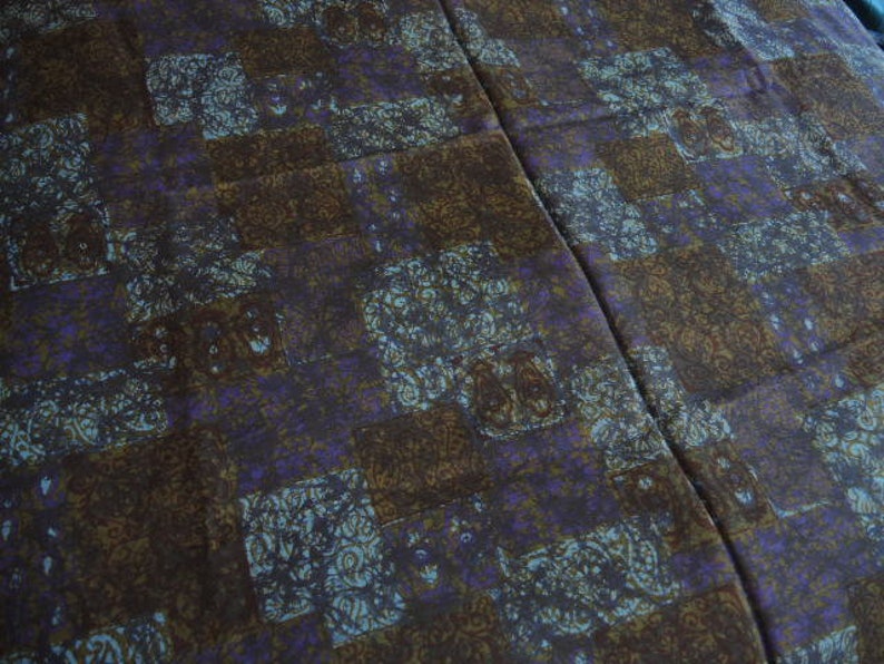 May include: A brown and purple patterned fabric with a geometric design. The fabric has a subtle sheen and a soft texture.
