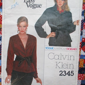 May include: A vintage sewing pattern featuring two women modeling Calvin Klein designs. The pattern includes a burgundy blazer with a black belt and a gray suit. The text "Easy Vogue" and "Calvin Klein 2345" are visible.