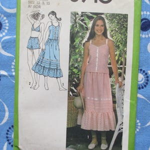 May include: Vintage sewing pattern featuring a woman in a pink two-piece outfit and illustrations of other outfits. The pattern includes a dress and a two-piece set. The background is a blue floral fabric.