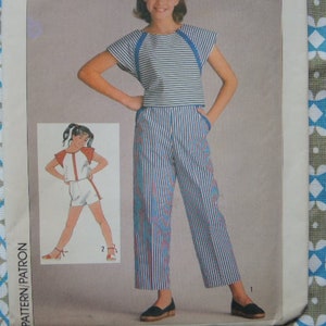 Può includere: Una maglia a righe blu e bianca con un paio di pantaloni abbinati. La maglia ha un collo rotondo e maniche corte. I pantaloni hanno una gamba larga e una vita alta.