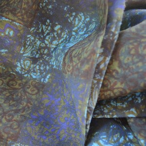 May include: A close-up of a brown and blue patterned fabric with a subtle sheen. The fabric is folded in a way that shows the pattern and texture.