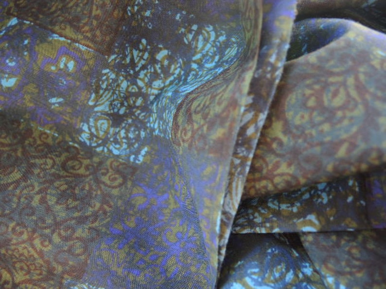 May include: A close-up of a brown and blue patterned fabric with a subtle sheen. The fabric is folded in a way that shows the pattern and texture.