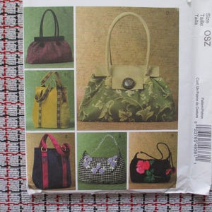 May include: A sewing pattern sheet featuring six different handbag designs. The bags vary in style, color, and size, including a burgundy textured bag, a yellow tote, and a green floral print bag with a button closure.